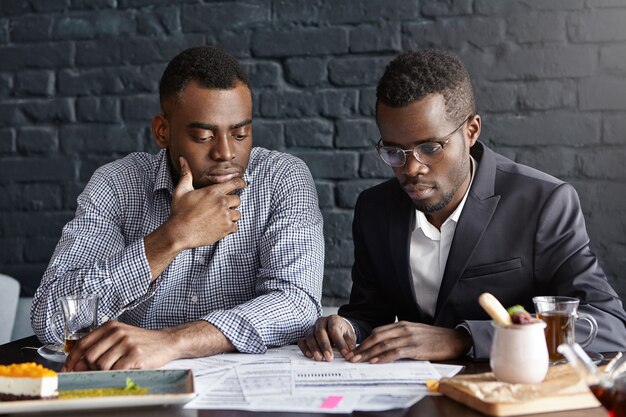 Two handsome dark-skinned executives having thoughtful and serious facial expression