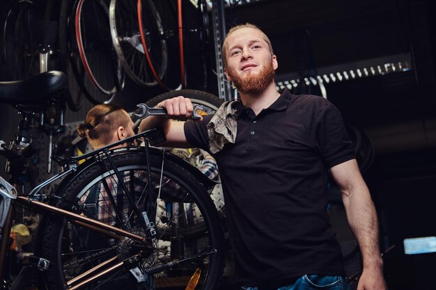 Two handsome stylish males working with a bicycle in a repair shop. Workers repair and mounts bike in a workshop.