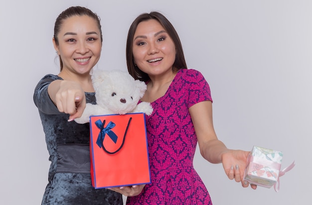 Two happy asian women holding paper bag with teddy bear