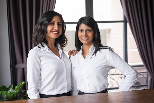 Two happy female coworkers in cafe.