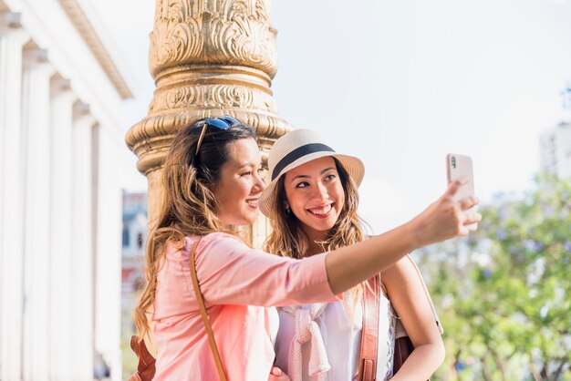 Two happy female friends taking self portrait from mobile phone