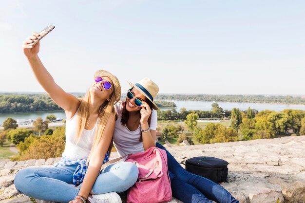 Two happy female friends taking selfie on cellphone