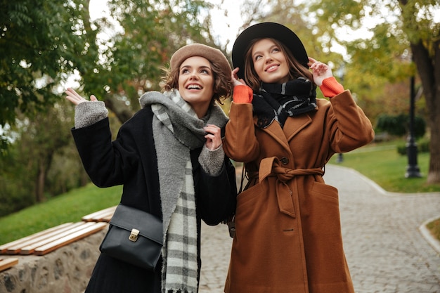 Two happy girls dressed in autumn clothes walking