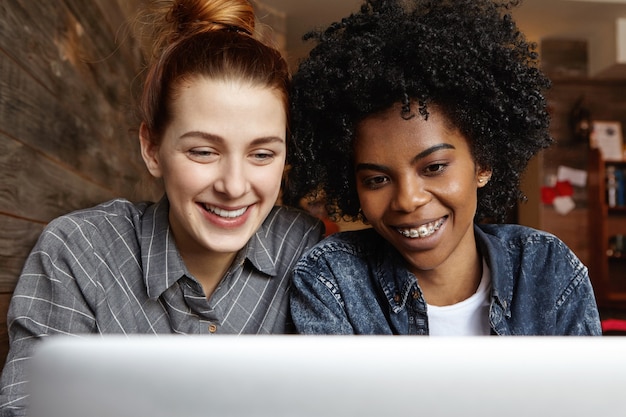 Two happy lesbians sitting in front of open laptop computer together