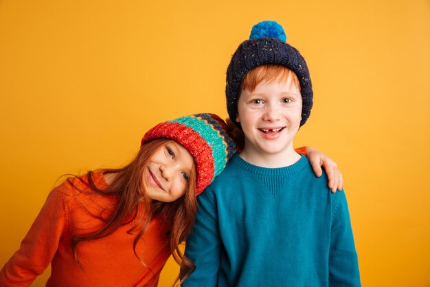 暖かい帽子をかぶっている2人の幸せな小さな子供。