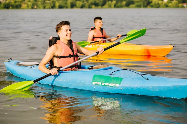 Two happy male kayaking on river