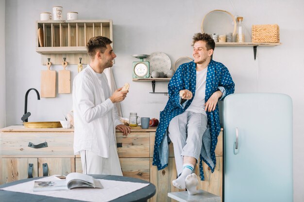 Two happy man having morning breakfast in kitchen