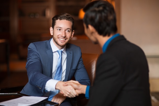 Two Happy Partners Shaking Hands in Cafe