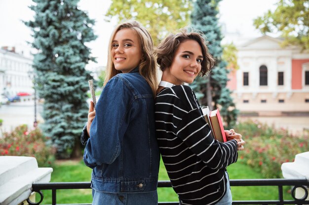 Two happy teenage girl holding books