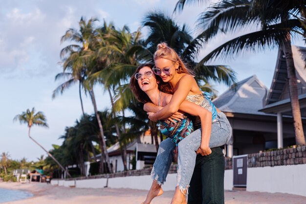 Two happy woman friends with sunglasses on vacation in tropical country