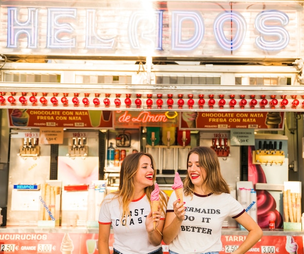 Two happy women holding ice cream at amusement park