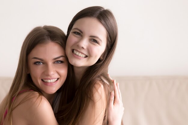 Two happy women hugging and looking in camera