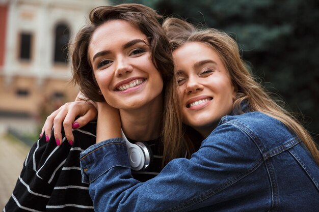 Две счастливые молодые девочки-подростки обнимаются