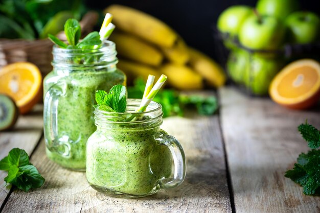 ほうれん草バナナ アップル キウイとミント ガラスの瓶と成分の 2 つの健康的なグリーン スムージー デトックス ダイエット健康的なベジタリアン フード コンセプト