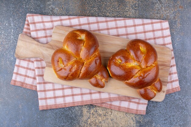 Two heart-shaped buns on a board on marble surface