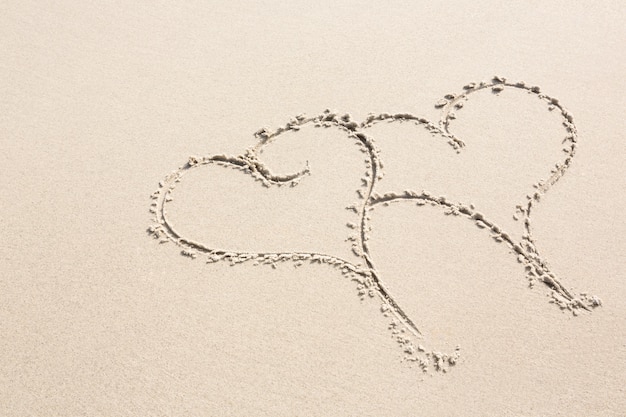 Free photo two heart shapes drawn on sand