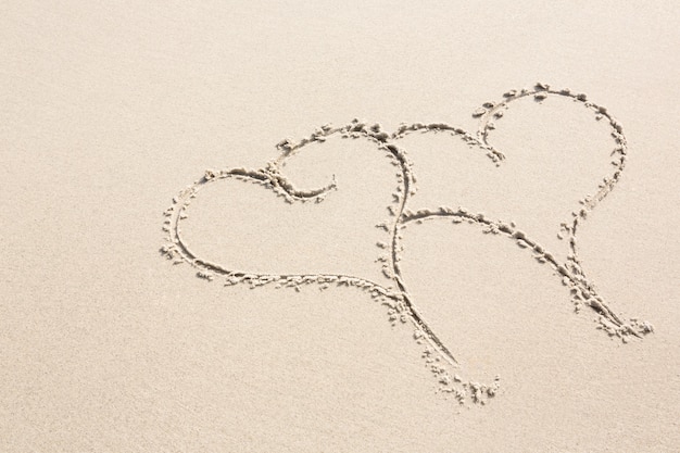 Two heart shapes drawn on sand