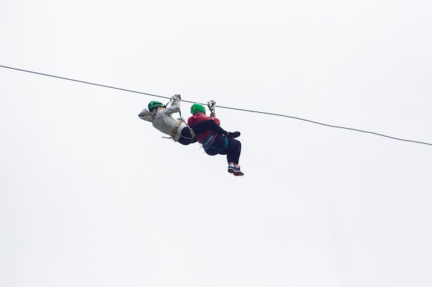 Foto gratuita due escursionista sulla zip line avventura contro il cielo in costa rica