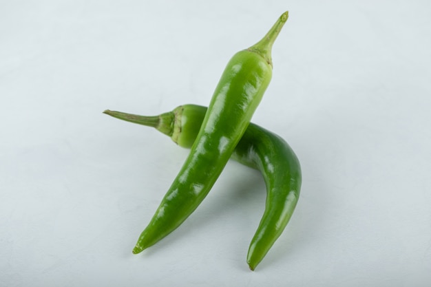 Two hot green chili peppers on white background. 