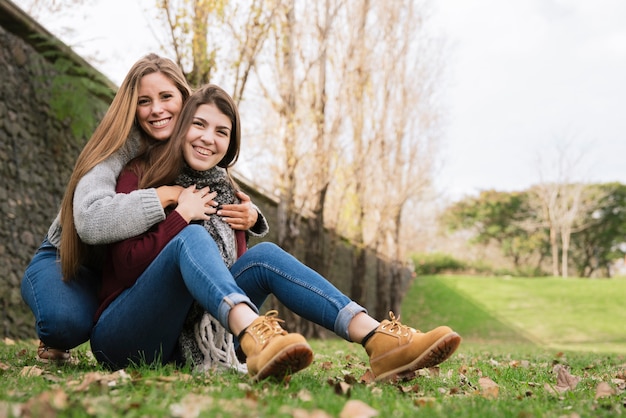 Two hugging young women sitting in the park