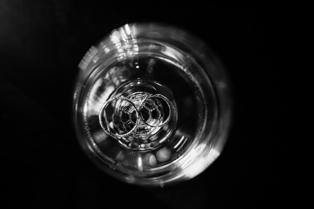 Two identical wedding rings lie at the bottom of a glass