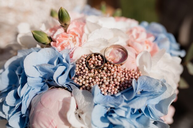 Two identical wedding rings lie on a wedding bouquet