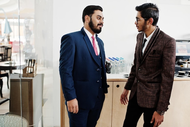 Two indian businessman in suits standing on cafe and discuss each other