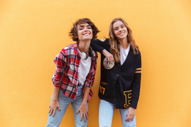 Two joyful young teenage girls posing while standing