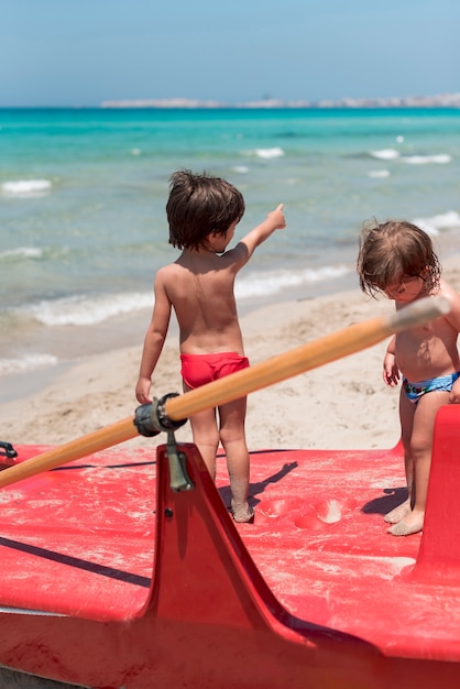 Two kids at the beach standing on paddle boat