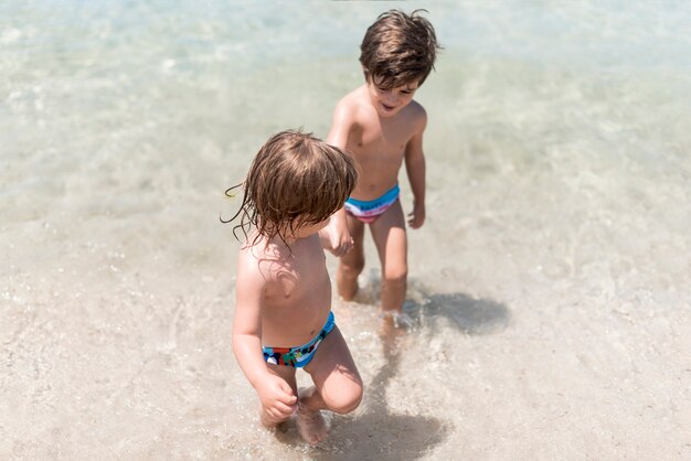 Двое детей играют в воде на берегу моря