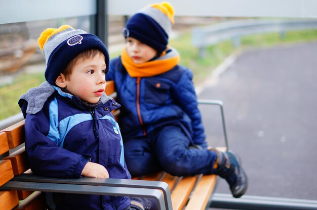 Two kids in winter clothes sitting on a bench