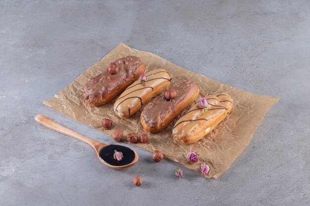 Two kinds of chocolate eclairs with spoon of chocolate on stone surface