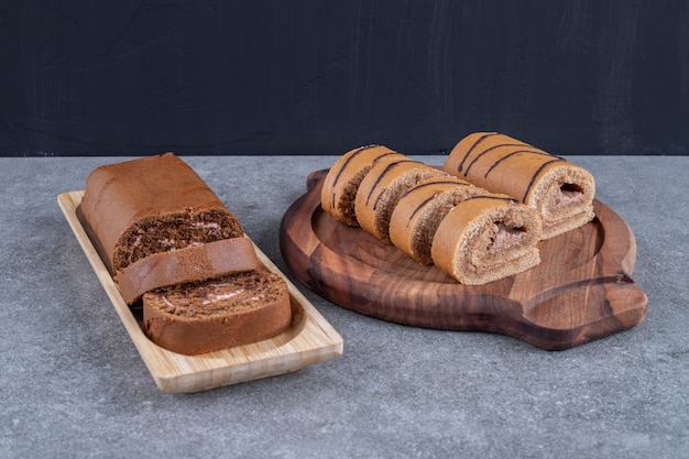 Two kinds of chocolate roll cake on wooden plates