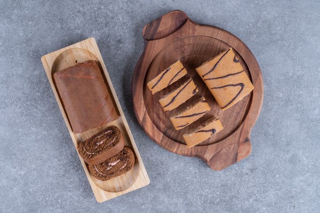 Two kinds of chocolate roll cake on wooden plates