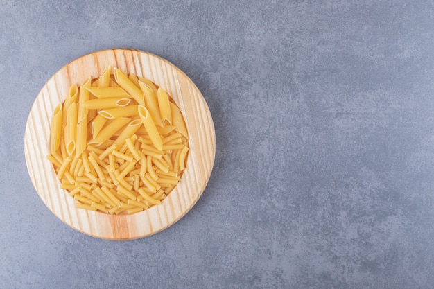 Two kinds of pasta on wooden plate.