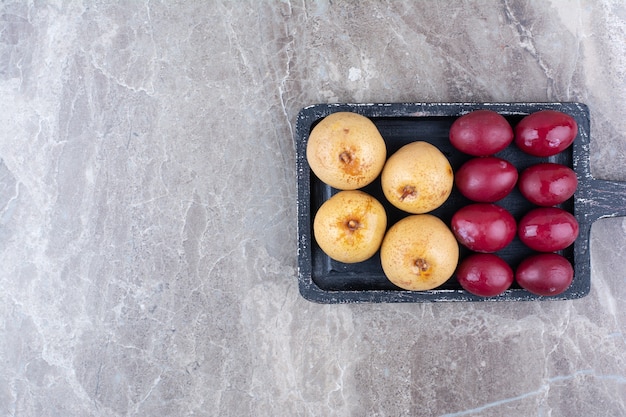 Foto gratuita due tipi di frutta in salamoia a bordo scuro.