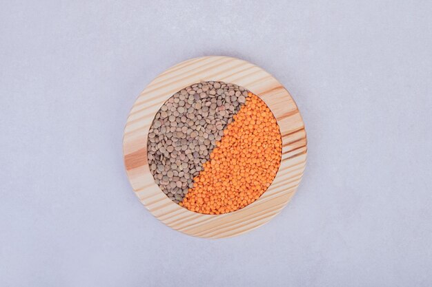 Two kinds of raw beans and lentils in wooden plate.