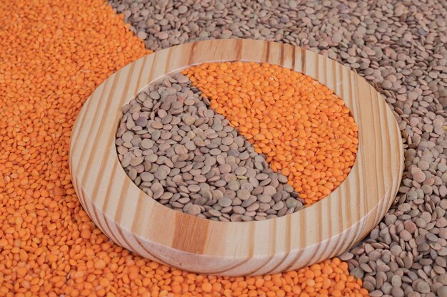 Two kinds of raw beans and lentils in wooden plate.