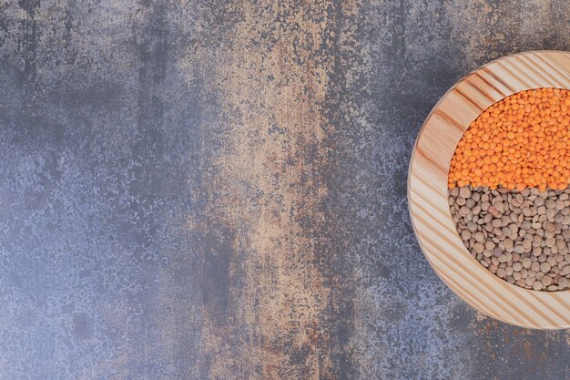 Free photo two kinds of raw beans and lentils in wooden plate.