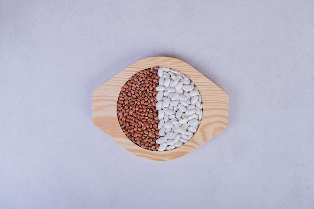 Two kinds of raw beans and peas in wooden plate.