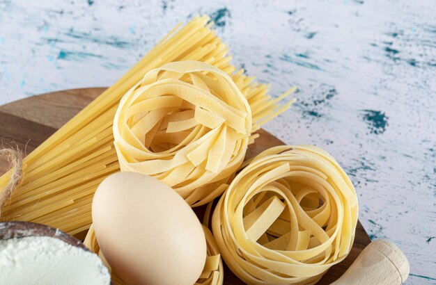 木の板に卵と小麦粉のボウルが入った2種類の生パスタ。