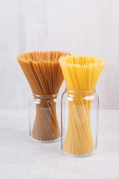 Two kinds of spaghetti inside glass jars.