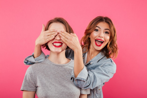 Two ladies friends covering eyes with hands.