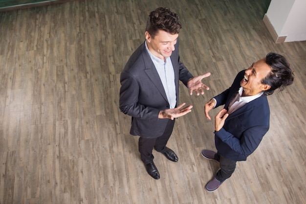 Two Laughing Business Men Chatting in Office Hall