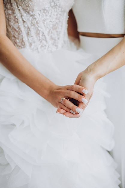 Две лесбиянки держатся за руки крупным планом в день своей свадьбы