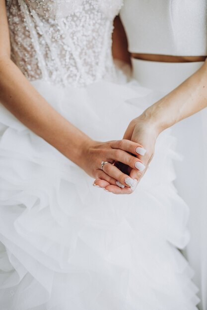 Two lesbian women holding hands close up on her wedding day