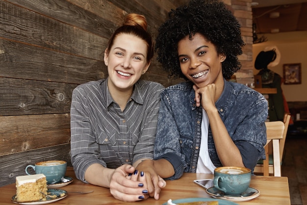 Two lesbians of different races having nice time together at coffee shop