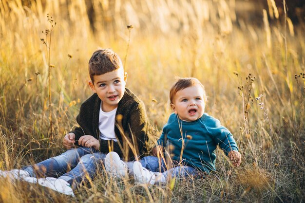 Two little baby brothers sitting together in field