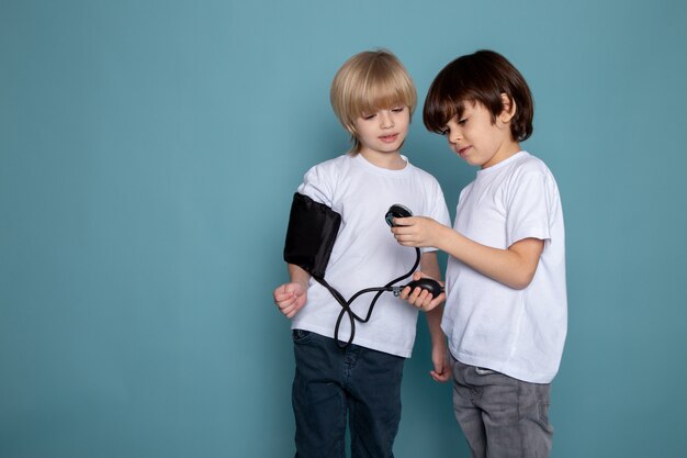 Two little boys one measuring others pressure on blue wall