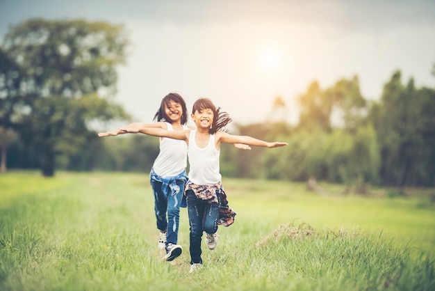 Two little cute girls are running on green grass. Best friends.